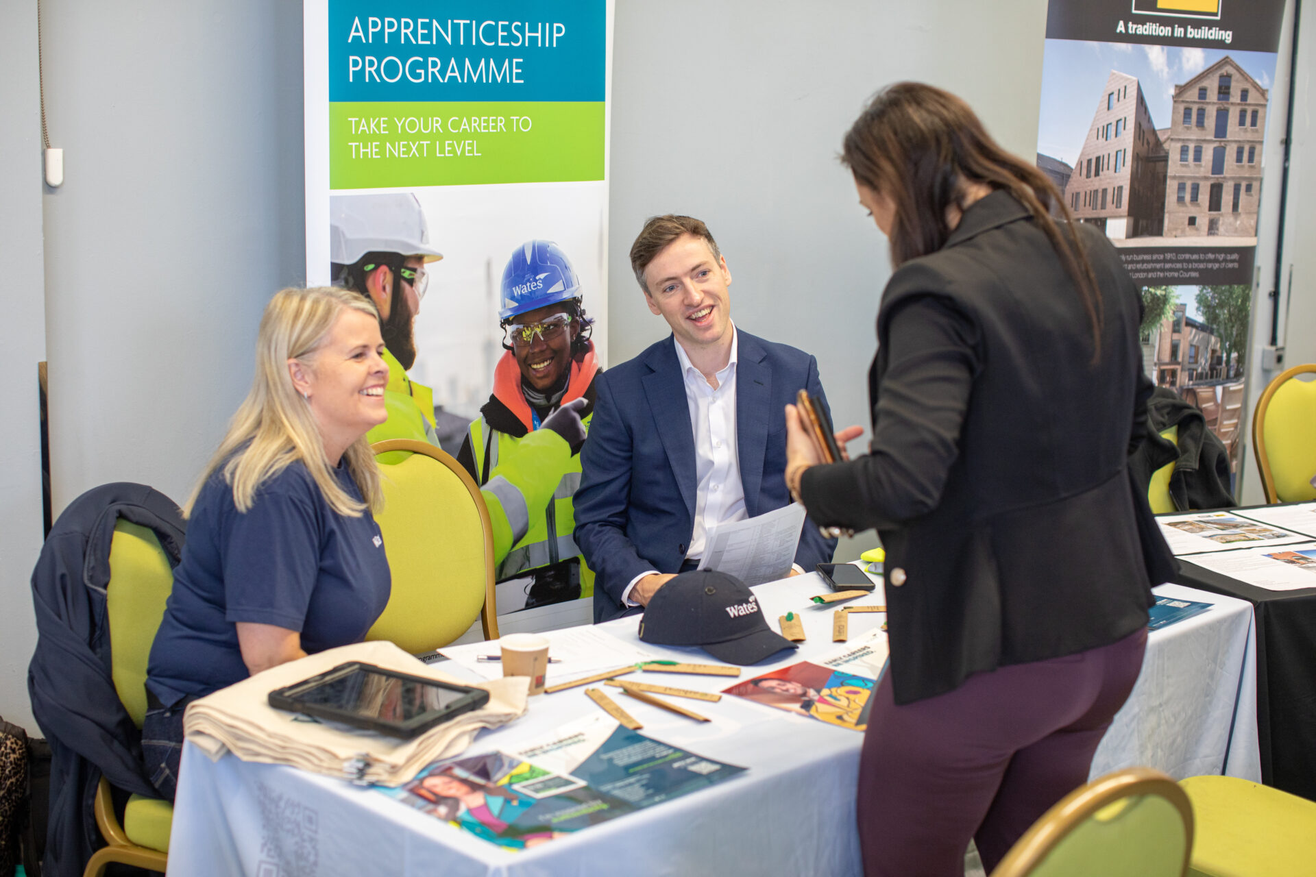 Employees from Wates construction talking to person at jobs fair