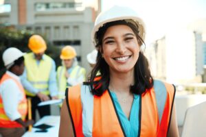 Young contractor standing outside while her colleagues work behind her