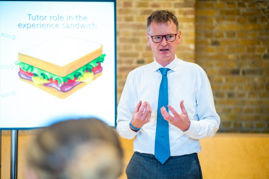 Man talking to room of adults about careers education