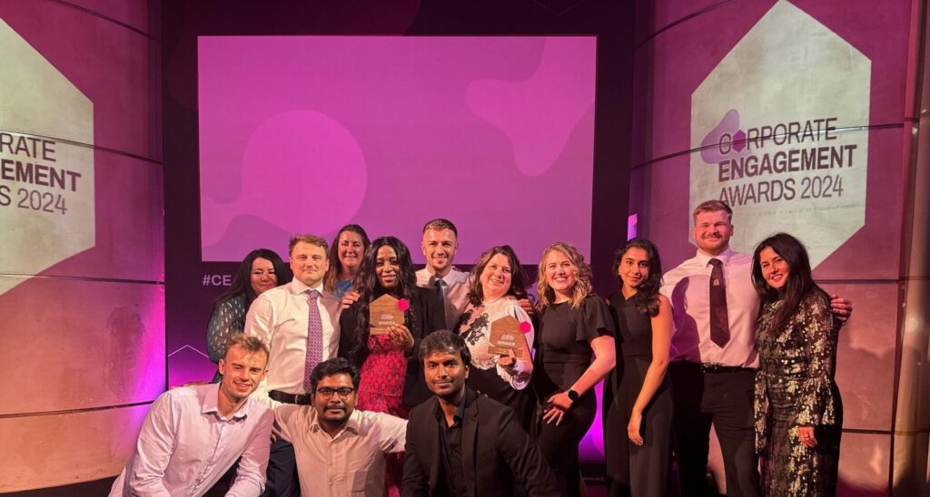 Group shot of award winners from CGI and Local London Careers Hub on stage, smiling and holding their awards.